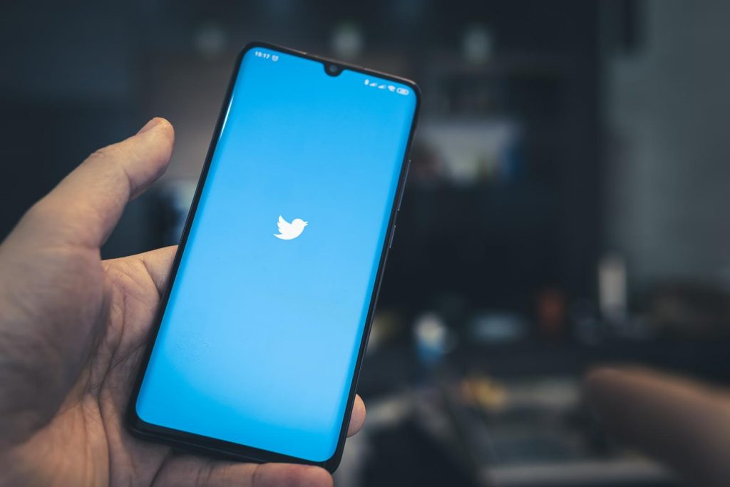 twitter on the screen of a black smartphone in a mans hand